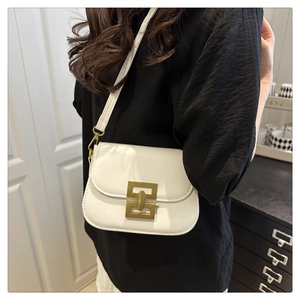 Close-up of vintage gold interlocking buckle on creamy white small crossbody bag