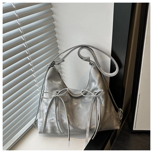 Detail of silver metallic hobo bag with twin bows and decorative zippers