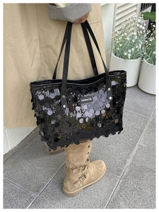 Detail of a black sequin tote bag with Creative Cat logo and elegant leather handles
