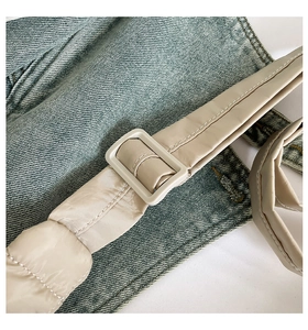 Detailed close-up of blue denim fabric with quilted beige strap and plastic buckle