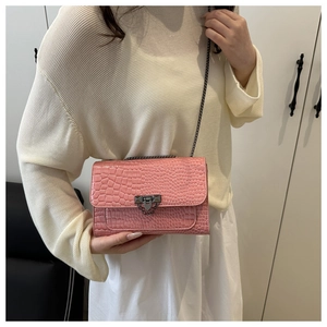 Detail of pink faux crocodile leather bag with fine chain strap and metal buckle