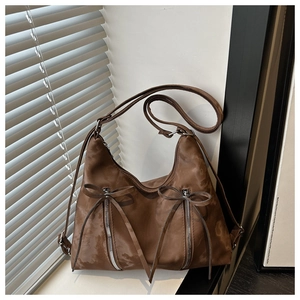 Detail of coffee brown hobo bag with bow ornaments and retro frosted texture finish