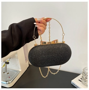 Detail of black sequined evening bag with golden bow clasp and metallic handle