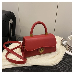 Detail der roten Ledertasche mit goldenem Rundverschluss und gewellter Klappe