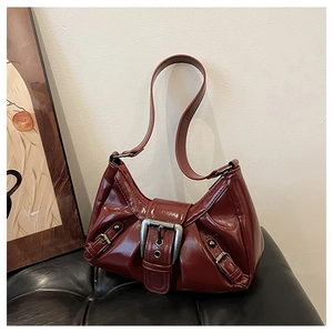 Detail of burgundy patent leather Y2K shoulder bag featuring large silver metal buckles