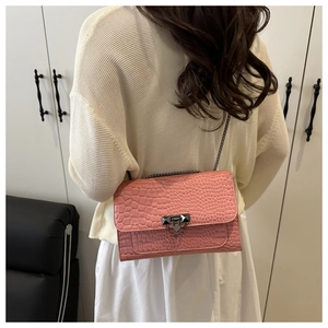 Detail of pink crocodile embossed handbag with high-gloss finish and metal chain strap