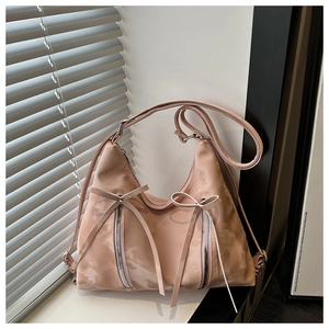 Close-up of hobo bag featuring decorative bow knots and dual vertical silver zippers