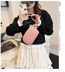 Detail of pink nylon crossbody bag with adjustable white buckle on female model