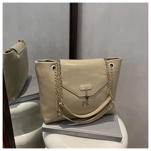 Detail of beige chain tote bag with a gold deer pendant on a stylish V-shaped flap