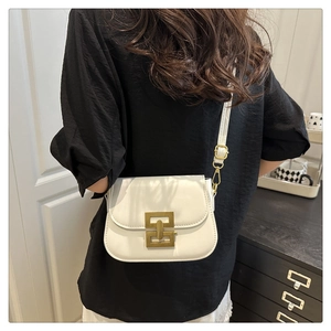 Detail of a minimalist cream shoulder bag featuring a vintage bronze interlocking buckle