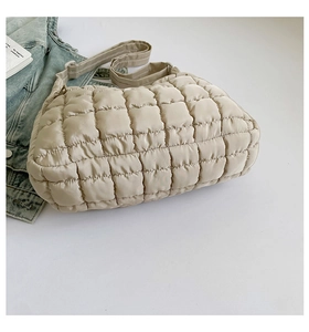Detail of beige quilted puffer tote bag with adjustable strap and puffy texture
