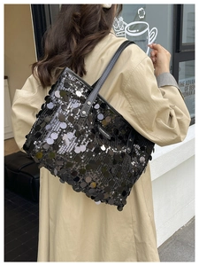 Close-up of black sequined tote bag with large reflective scales and leather strap
