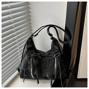 Detail of the black tote bag featuring unique bow zipper pulls and textured material