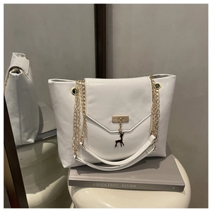 Detailed view of white tote bag featuring gold deer charm and textured leather