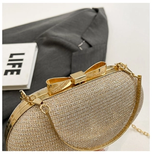 Close-up of champagne sequin evening bag with a gold bow clasp and metallic chain