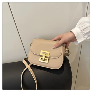 Close-up of beige square crossbody bag featuring a golden geometric clasp and leather strap