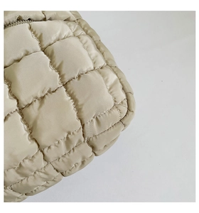 Detail of champagne quilted nylon bag with square stitching and metallic zipper