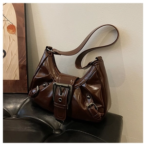 Detail of dark brown patent leather hobo bag with vintage metal buckle on black leather bench