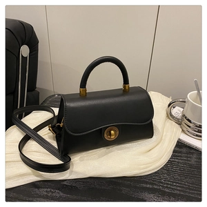 Detail der schwarzen matten Handtasche mit goldenem Drehverschluss und Metallbeschlägen