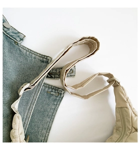 Detail of light beige quilted puffer bag showing thick strap and puffy nylon texture