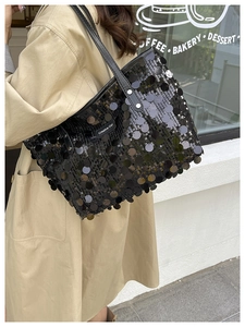 Detail of black sequin tote bag with leather straps and Creative Cat label on a model