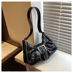 Detail of glossy black patent leather shoulder bag with bold silver metal buckle accents