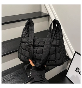 Detail of black quilted puffer tote bag with glossy texture and adjustable wide shoulder strap