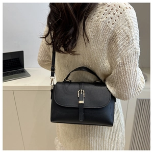 Close-up of black lychee grain handbag with gold buckle in a professional office setting