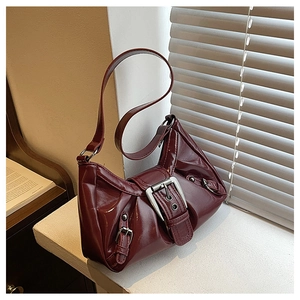 Detail of dark red wrinkled patent leather shoulder bag with silver metallic buckle accents