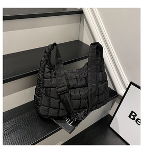 Macro detail of black quilted puffy tote bag with soft padded texture and crossbody strap