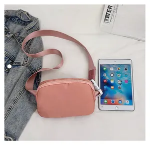 Pink nylon crossbody bag shown next to a tablet for size comparison and scale
