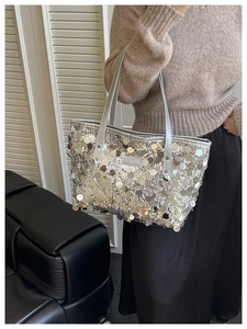 Detail of silver sequin tote bag with metallic texture on a model wearing a beige sweater