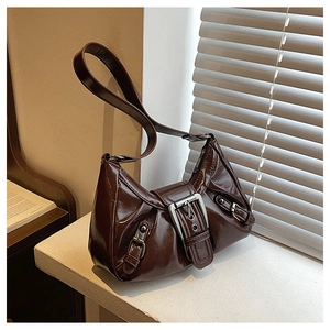 Detailed macro view of dark brown patent leather shoulder bag with silver buckle accents