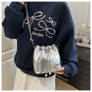 Detail of silver metallic bucket bag with pearl drawstring and elegant chain strap