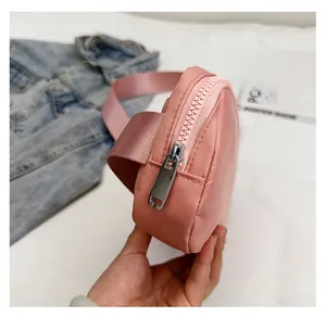Detail of pink nylon crossbody bag featuring smooth large zippers and metal pullers
