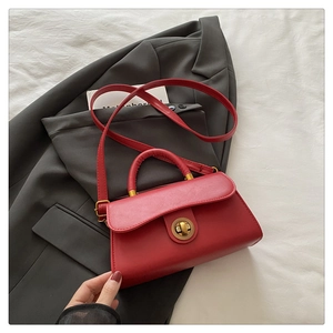 Rote rechteckige Handtasche mit goldenem Drehverschluss und Schultergurt im Detail