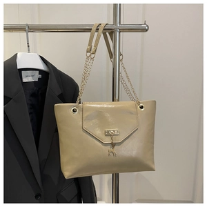 Detail of glossy beige patent leather tote bag with gold chain and deer charm