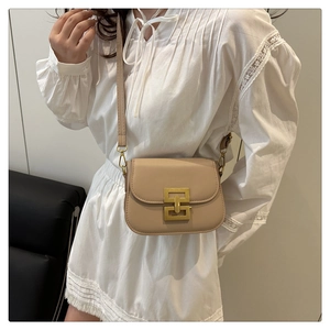 Detail of a beige mini crossbody bag featuring a unique golden interlocking metal buckle