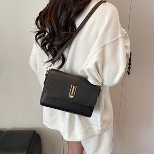 Chic black litchi leather crossbody bag with brown strap shown on a female model