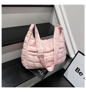 Close-up of pink quilted puffer tote bag with adjustable wide strap on modern stairs