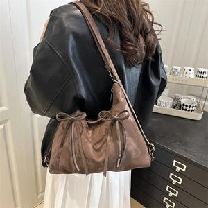 Brown satin tote bag with stylish bow accent and vertical zipper details shown on shoulder