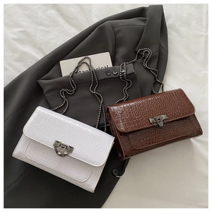 Detail of white and brown crocodile embossed bags with metal buckles on a blazer
