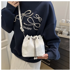 Detail of white bucket bag with metallic chain drawstring and large pearl accents