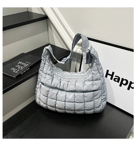Detailed close-up of light blue quilted puffer tote bag with adjustable wide shoulder strap