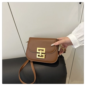 Detail shot of a brown saddle bag with a distinctive golden geometric interlocking buckle