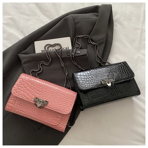 Close-up of crocodile pattern leather texture with metal chain and luxury flap buckle