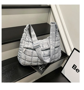 Detailed macro view of light blue quilted puffer bag texture and adjustable strap