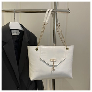 Detailed close-up of white leather tote bag with gold deer charm and chain strap