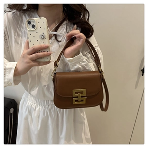 Close-up of a brown vintage crossbody bag with a distinctive golden interlocking metal clasp