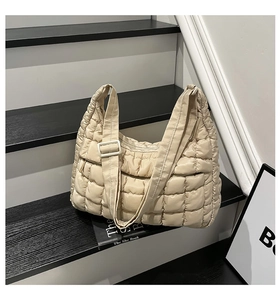 Detailed close-up of beige quilted puffy tote bag with wide strap on modern stairs